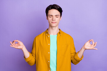 Photo of nice brunet millennial guy do yoga wear yellow shirt isolated on violet color background