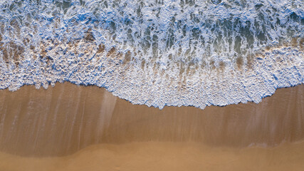 Fototapeta na wymiar Aerial top view of shore waves washing the sand of the beach in Andalusia, Spain. Spanish sand beach seen from above with beautiful colors and patterns