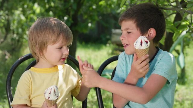 handsome male children with delight lick their tongues on cool ice cream during summer holiday viema and point their fingers up