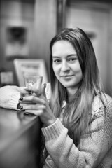 Young beautiful girl drinking coffee in a cafe, black and white photo.