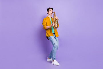 Full body photo of cool brunet young guy play sax wear brown shirt jeans isolated on violet color...