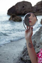Natural beauty of as young woman in the coast side in a  vintage dress with a mirror