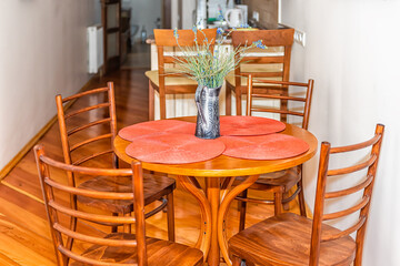 Wooden brown narrow apartment kitchen with table chairs and flower decorations in old-fashioned European house