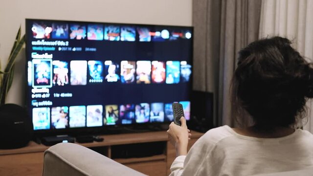 close up on the hand pressing the TV remote to select a movie or show to watch on TV. in the living room 4k