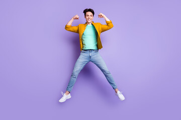 Full length photo of young man happy positive smile jump show hands muscles isolated over violet color background