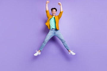 Fototapeta na wymiar Full body photo of hooray brunet young guy jump wear shirt jeans isolated on violet color background