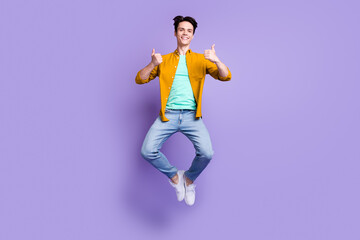 Fototapeta na wymiar Full length photo of young man happy positive smile jump up show thumb-up fine isolated over violet color background