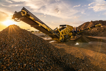 Heavy and mobile machinery in a quarry to transform stone into construction material - obrazy, fototapety, plakaty