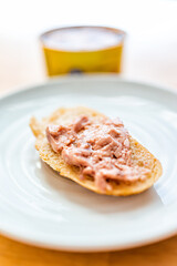 Canned cod liver in oil spread fish on toast bread plate on table with background of can as healthy omega 3 rich food popular in Russian cuisine
