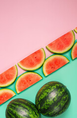 Whole and slices of fresh watermelon on pink and green  background.Flat lay with copy space.Trendy food photography.Fancy wallpaper.
