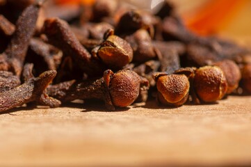 Dried clove seeds, in shallow focus, on the wooden table
