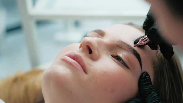 Model face during permanent makeup eyebrows process in beauty salon