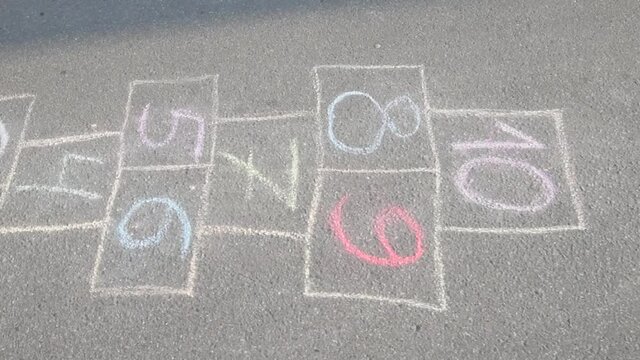 Close-up video of chalk painted hopscotch on asphalt. School yard. Back to school. Outdoor activities for kids.