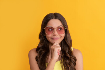 Fototapeta premium happy dreamy kid in summer glasses has curly hair on yellow background, hairstyle