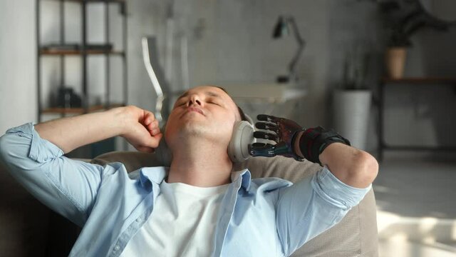Relaxed man with black bio hand prothesis listens to music