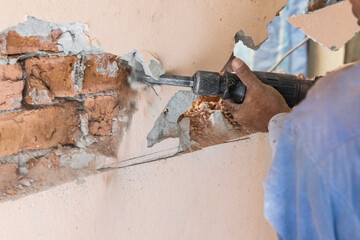 Worker use demolition hammer drill to break up wall surface. Motion blur intended.