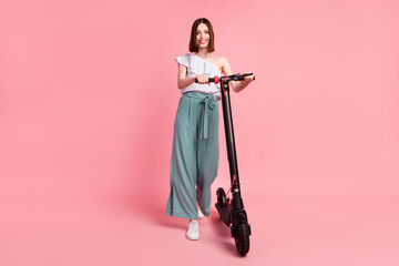 Full length photo of young girl happy positive smile walk trip electric scooter isolated over pastel color background