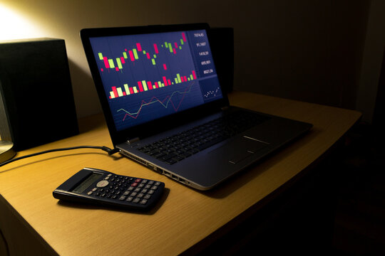 Screen with investment information in the stock market with technical indicator tools on the computer, with a calculator next to it. Business concept.