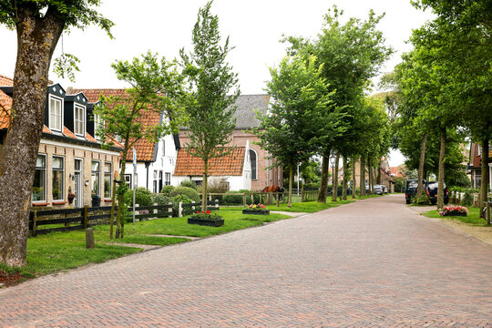 Street with houses and trees in the village of Hollum on Ameland, one of the Dutch Wadden islands.