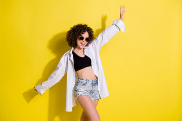 Photo of sweet shiny young woman dressed black top dark eyewear dancing smiling isolated yellow color background
