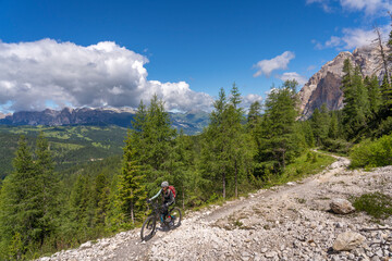 Fototapeta na wymiar pretty active senior woman riding her electric mountain bike up to Valparola Pass in the Alta Badia Dolomites , South Tirol and Trentino, Italy