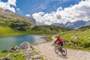 pretty active senior woman riding her electric mountain bike at Lago de in the Fanes high Valley,...