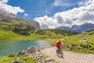 Fototapeta na wymiar pretty active senior woman riding her electric mountain bike at Lago de in the Fanes high Valley, part of Fanes-Sennes-Braies nature park in the Alta Badia Dolomites, South Tirol and Trentino, Italy 