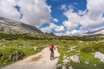 Obraz premium pretty active senior woman riding her electric mountain bike in the Fanes high Valley, part of Fanes-Sennes-Braies nature park in the Alta Badia Dolomites, South Tirol and Trentino, Italy 