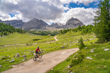 pretty active senior woman riding her electric mountain bike in the Fanes high Valley, part of Fanes-Sennes-Braies nature park in the Alta Badia Dolomites,  South Tirol and Trentino, Italy
