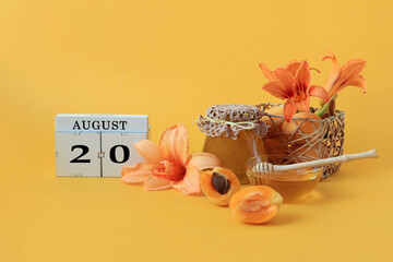  Calendar for August 20 : the name of the month of August in English, cubes with the number 20, honey, a jar of jam, apricots, daylily flowers on a yellow background.