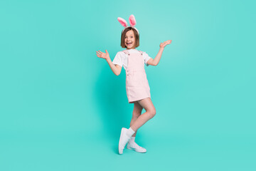 Photo of funky impressed school girl wear pink overall bunny ears smiling rising arms isolated teal color background