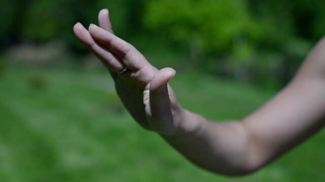 Close - up of a woman hand performing a yoga asana during meditation in a park. Calm down and relax