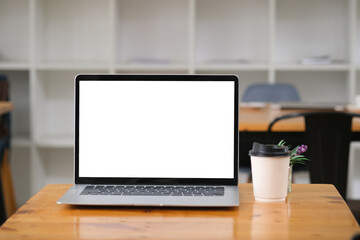 Fototapeta premium Mock up with blank screen of laptop computer and cup of coffee on the wooden desk in cafe.