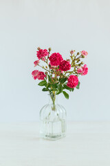 Romantic bouquet of pink roses in a glass vase on a white background.