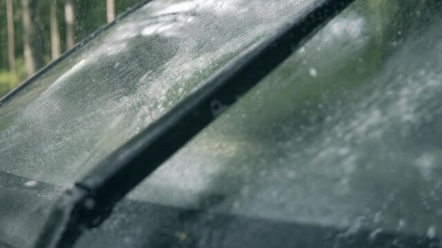 Spraying car windshield washer fluid slow motion, working wipers 