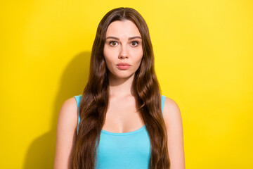 Photo portrait serious girl with long hair in blue singlet isolated bright yellow color background