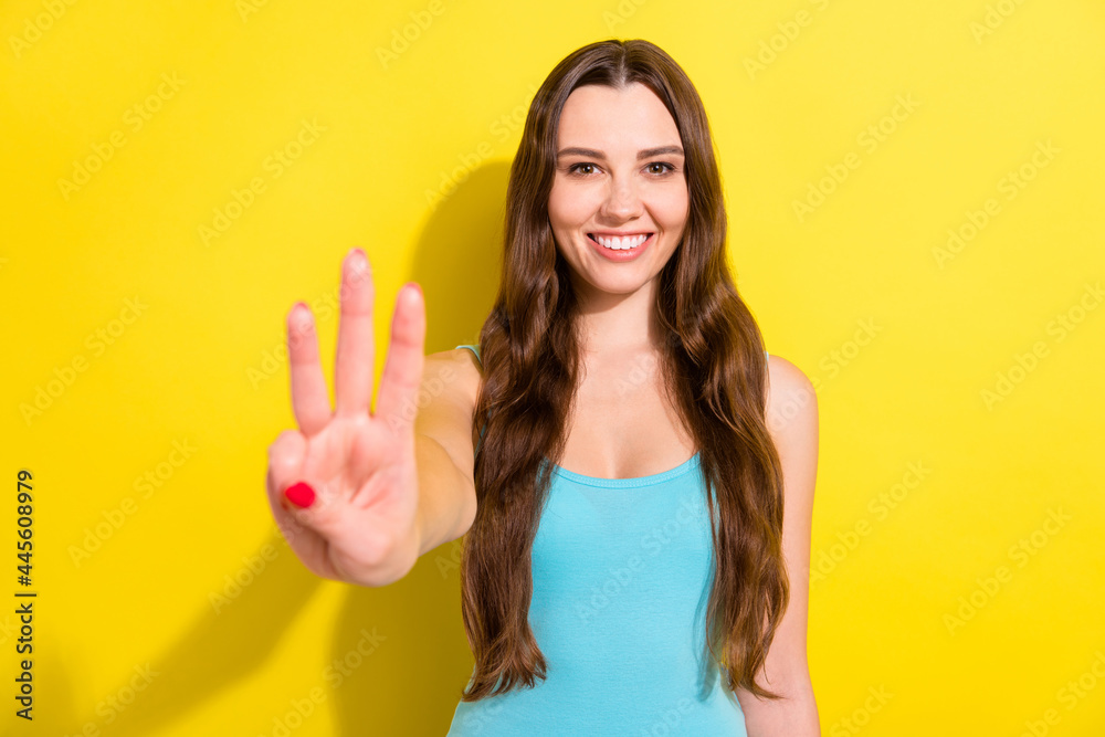 Sticker Photo of optimistic brunette hairdo young lady show three fingers wear teal top isolated on vivid yellow color background