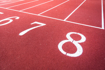 Running starting position with number sign and white lane of the standard racetrack. Sport equipment and background photo. Close-up and selective focus.