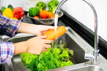 close up hand of healthy girl Washing vegetables in the kitchen sink