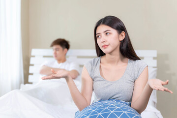 Unhappy sad couple sitting in bed away from each other , ignoring avoiding sex in bed , young wife...