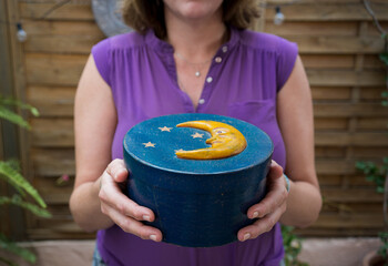 Anonymous woman holding blue and vintage box with yellow half moon on lid