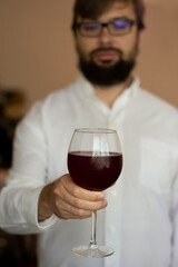 Close up side view of man holding glass with red wine enjoying summer mood and food