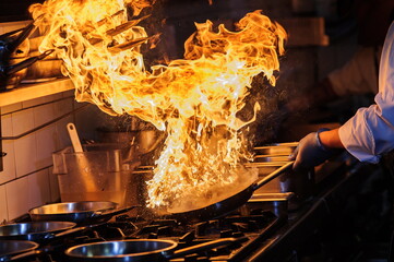 Chef is stirring vegetables in wok on open fire