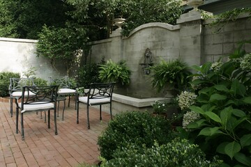 Backyard park patio seating with stone wall, bushes, and trees