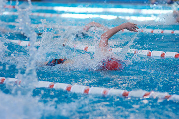 a beanie swimmer stretches out his arms during a breaststroke workout in the pool, blurred focus