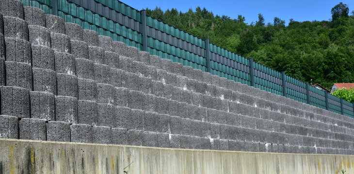 St&uuml;tzmauer aus grauen runden Pflanzsteinen zur Hangsicherung und Abgrenzung eines Wohngrundst&uuml;cks gegen die tiefer liegende Stra&szlig;e