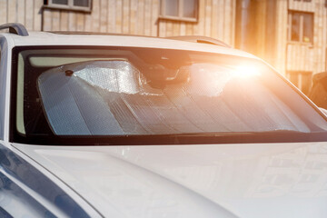 Sun visor or sun reflector on car windshield protects car in parking lot. There is light from sun...