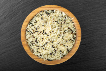 Wild rice in a bowl against a black background.