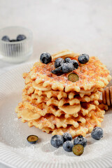 a stack of waffles with blueberries and honey