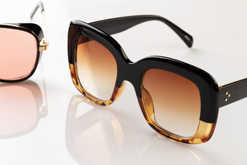 Sunglasses on a white reflective surface. Fashionable, stylish accessories.  Use it for a vacation...